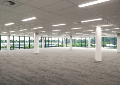 An empty office space in a multi-storey building, with a grid ceiling.