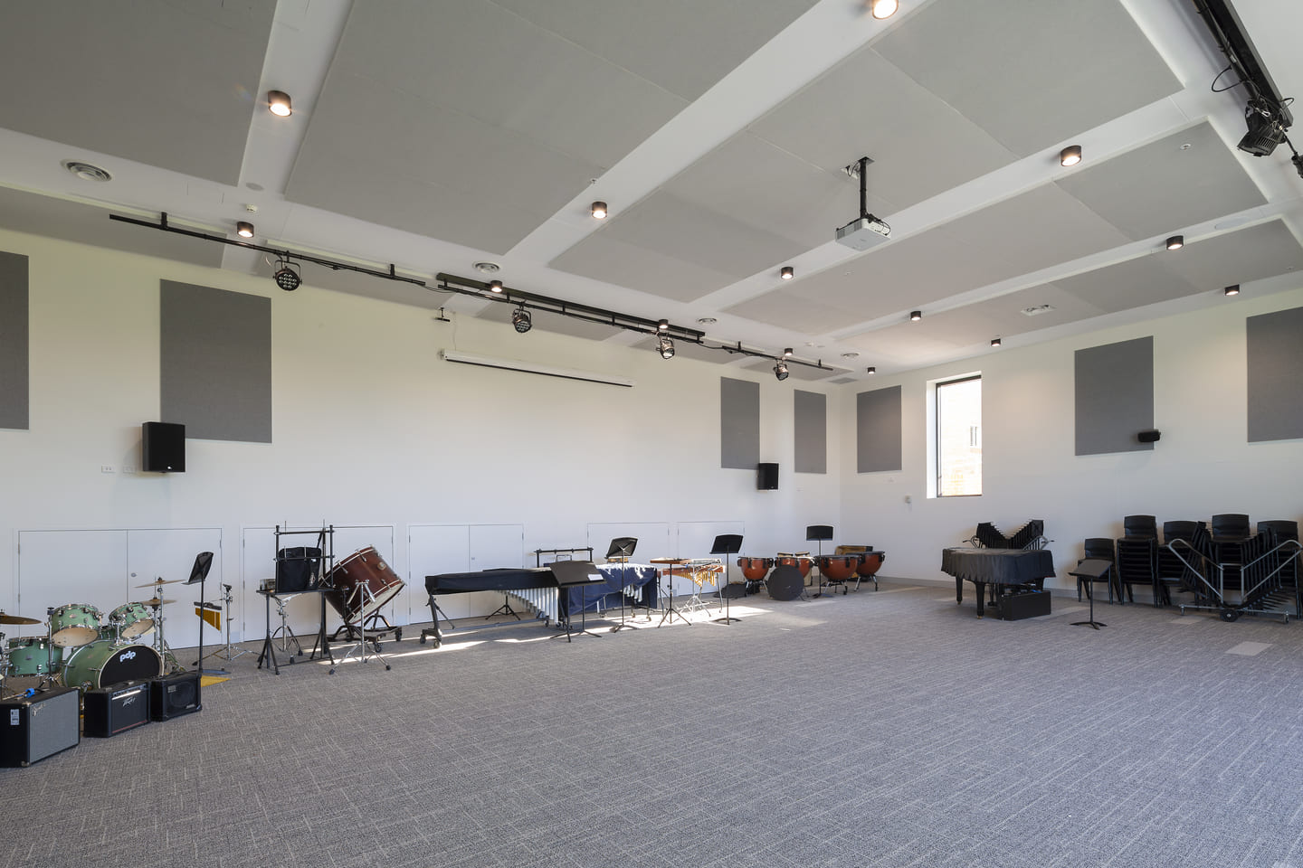 Rows of desks in an office space, with an acoustic ceiling and glazed partitions.